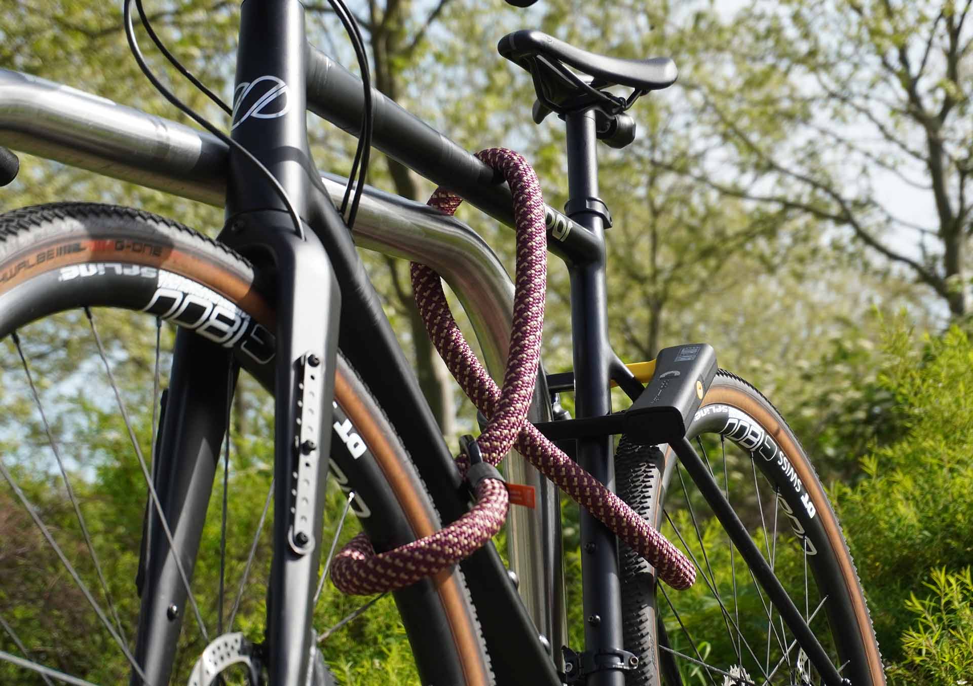 Fahrrad am Hinterrad, Vorderrad und Fahrradrahmen mit D-lock Bügelschloss und eyelet-Textilseil in chateau red am Fahrradständer angeschlossen