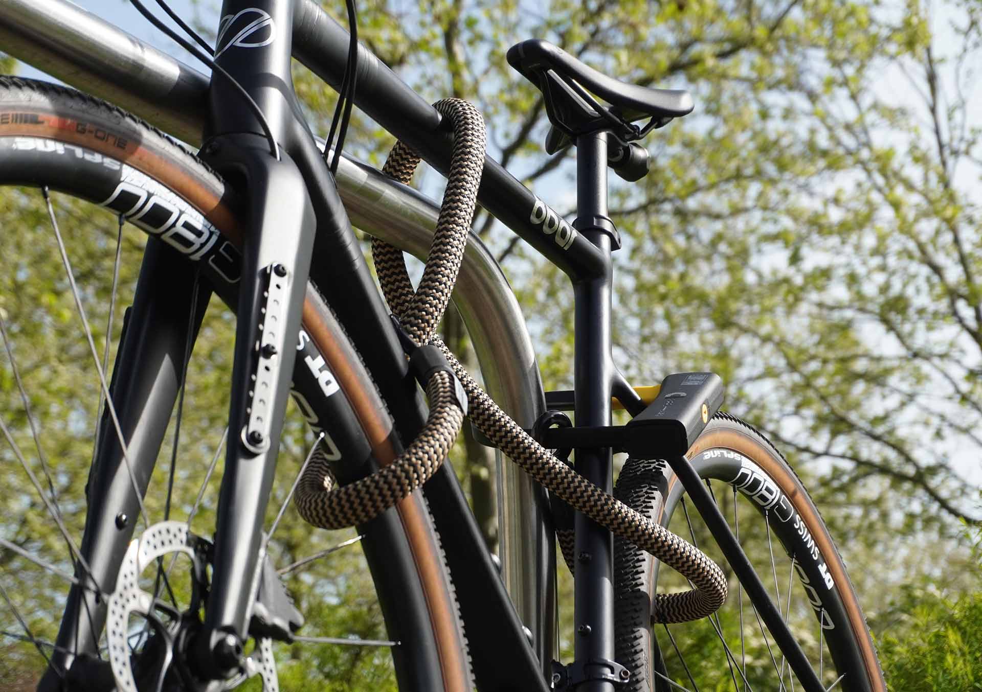 Fahrrad am Hinterrad, Vorderrad und Fahrradrahmen mit D-lock Bügelschloss und eyelet-Textilseil in wild hemp am Fahrradständer angeschlossen