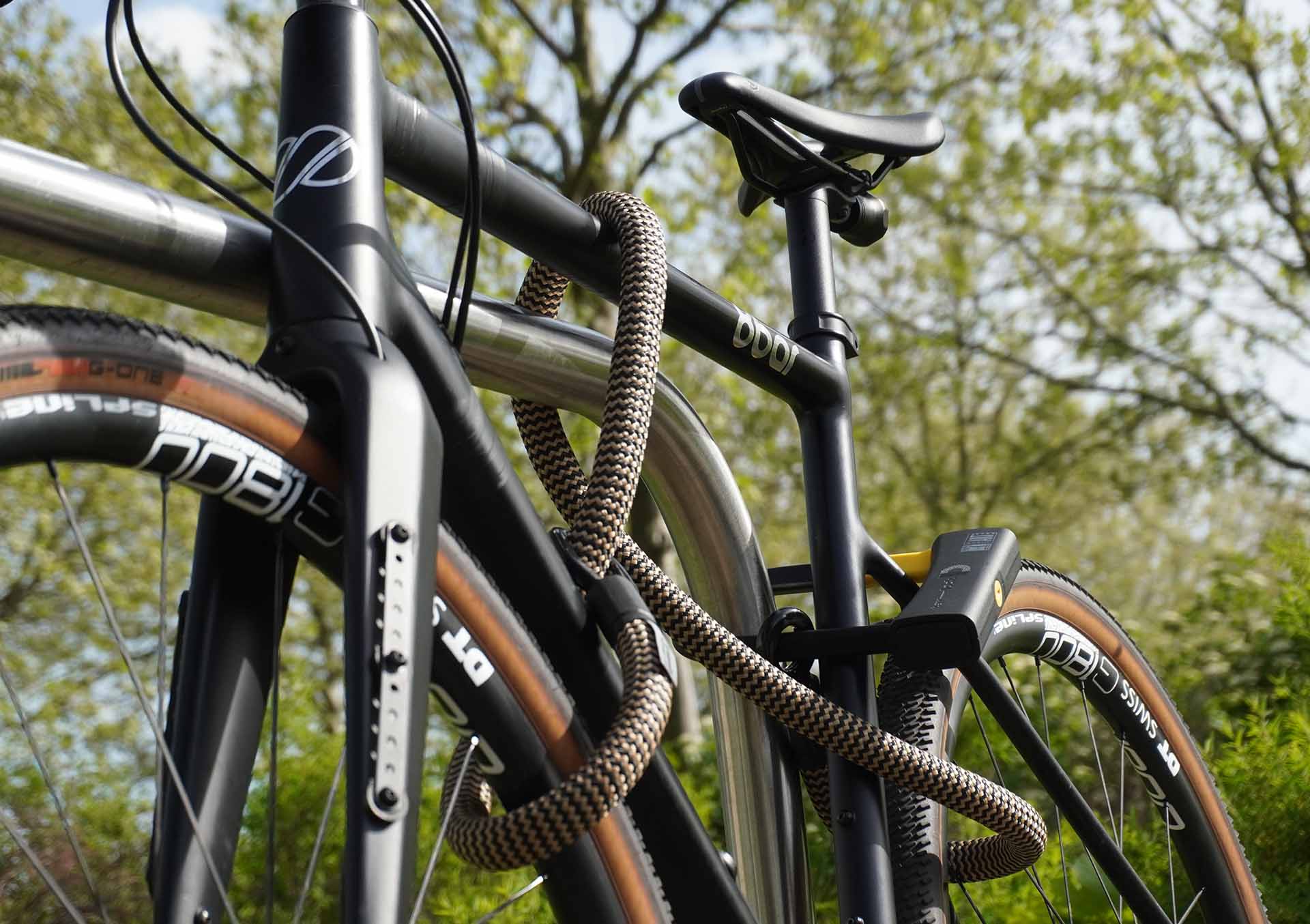 Bicycle connected to the rear wheel, front wheel and bicycle frame with D-lock U-lock and eyelet textile cable in wild hemp on the bicycle stand
