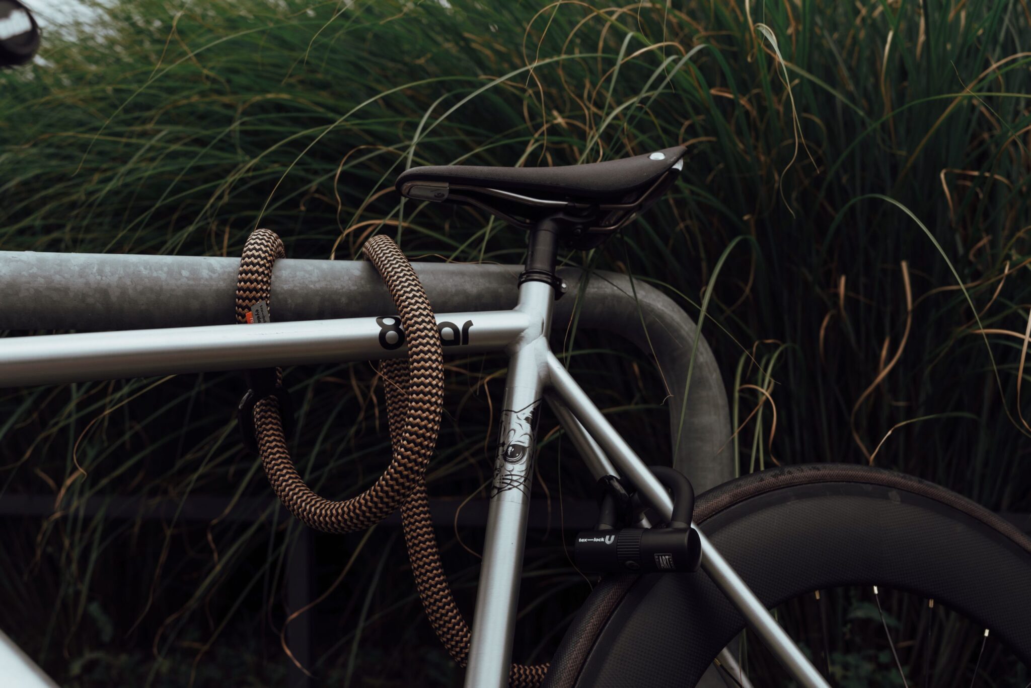 Silbernes 8bar Fahrrad mit tex-lock eyelet orange und U-Lock an Fahrradständer angeschlossen
