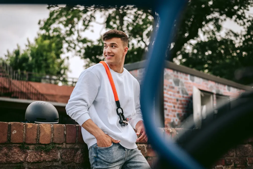 oranges Fahrradschloss um Schulter eines male Models mit weißem Pullover