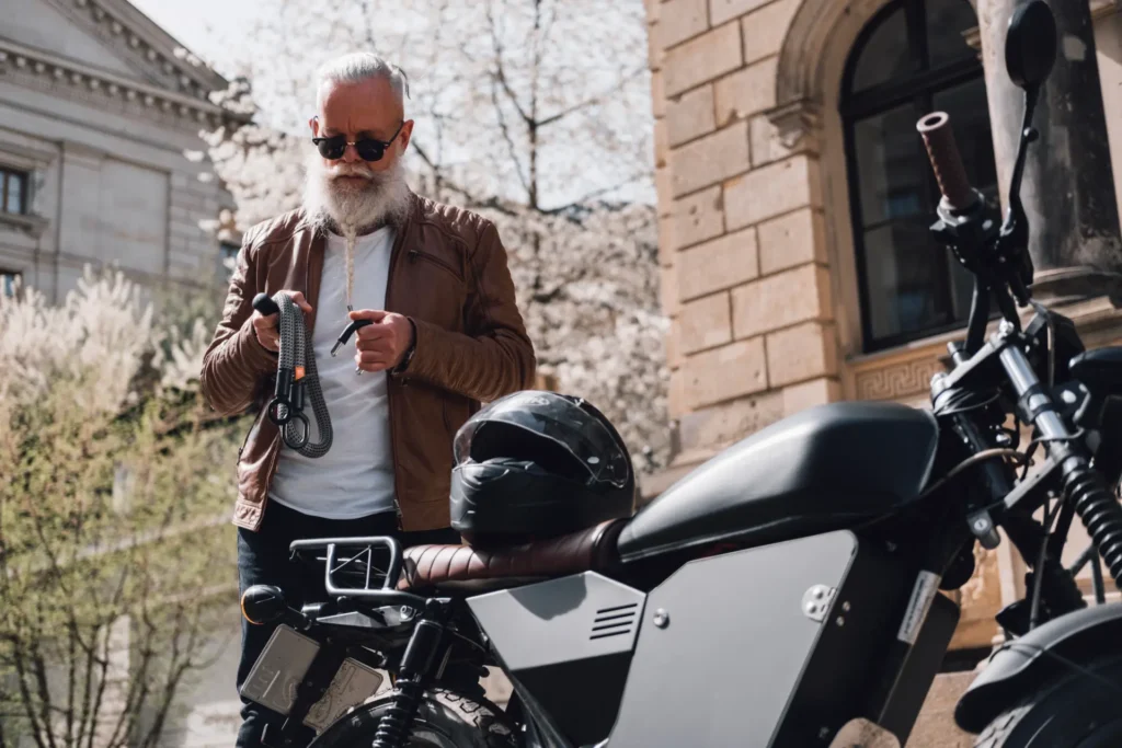 grau-schwarzes Textilschloss mit älterem male Model vor Motorrad