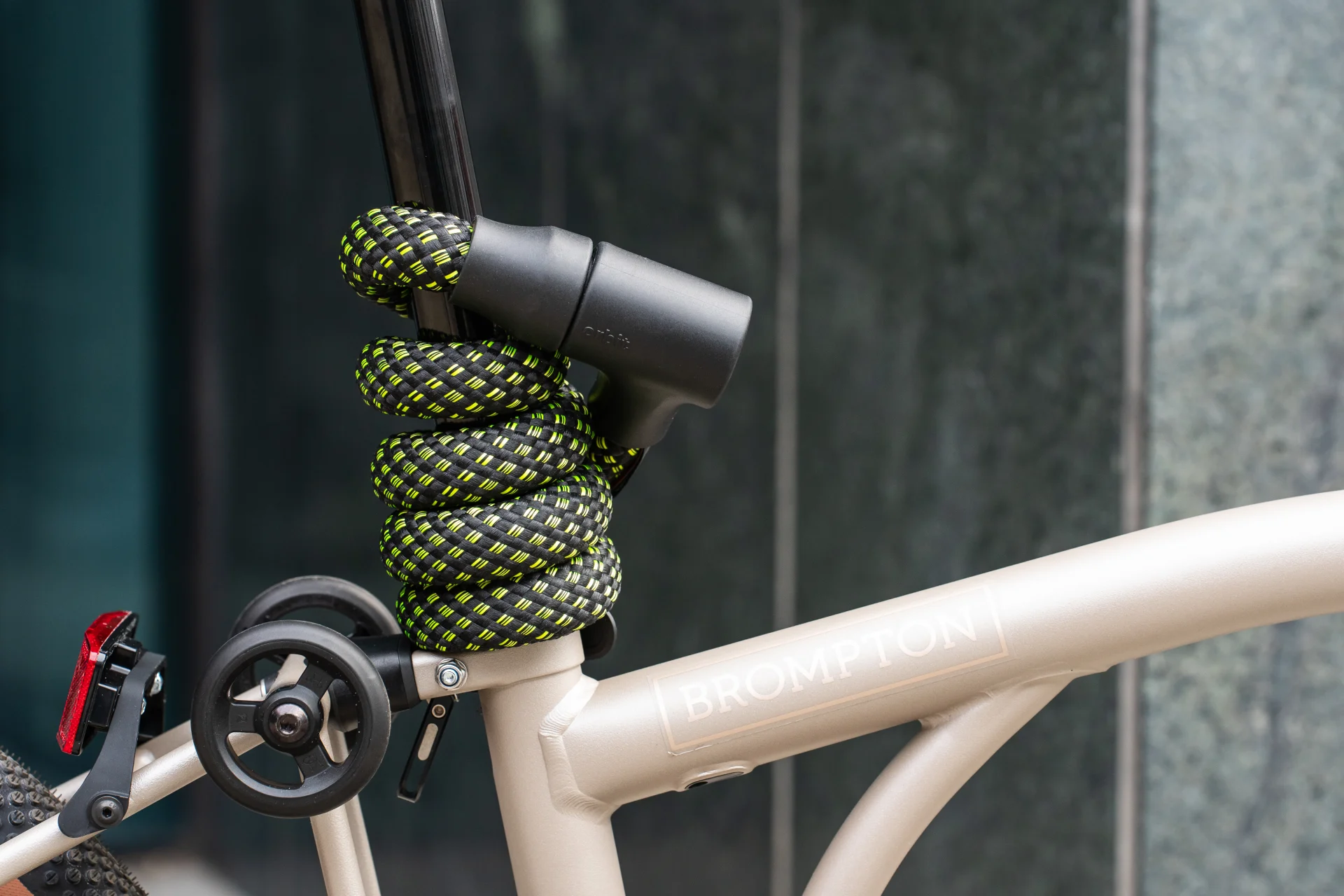 Schwarzes Fahrradschloss mit Neonmuster um Sattelstange von Brompton Faltrad gewickelt