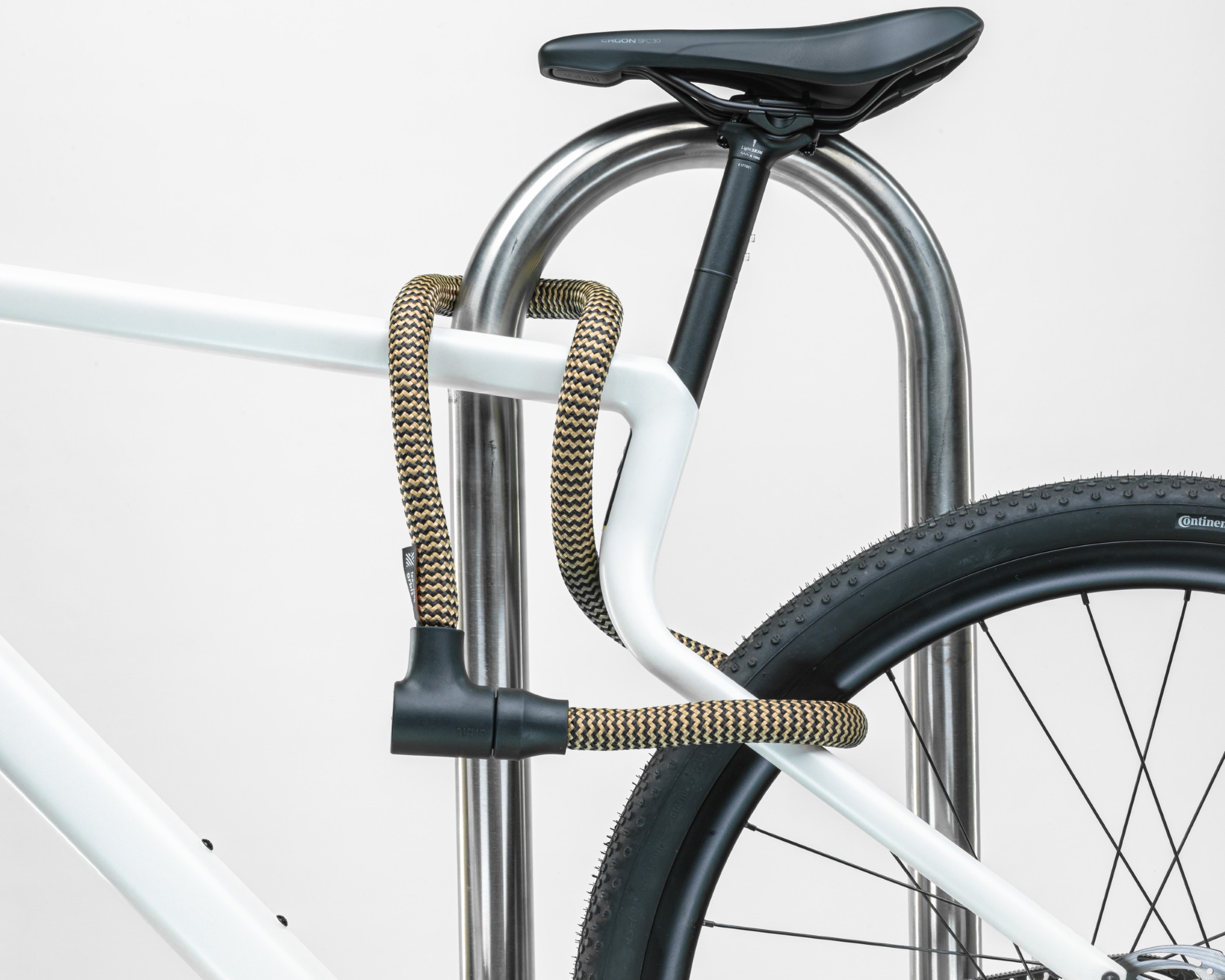 Black and gold texlock orbit textile lock secures several bike parts to the bike stand