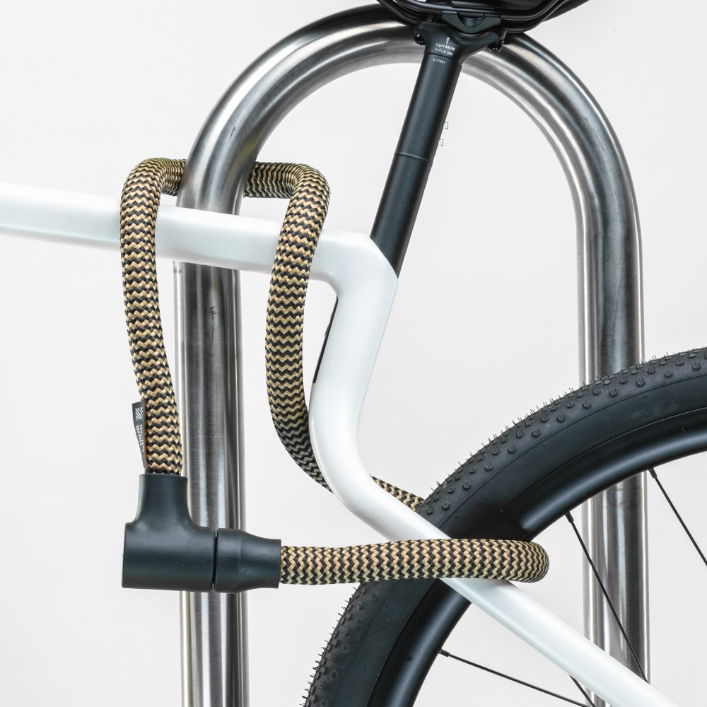 schwarz-goldenes texlock orbit Textilschloss sichert mehrere Fahrradteile am Fahrradständer