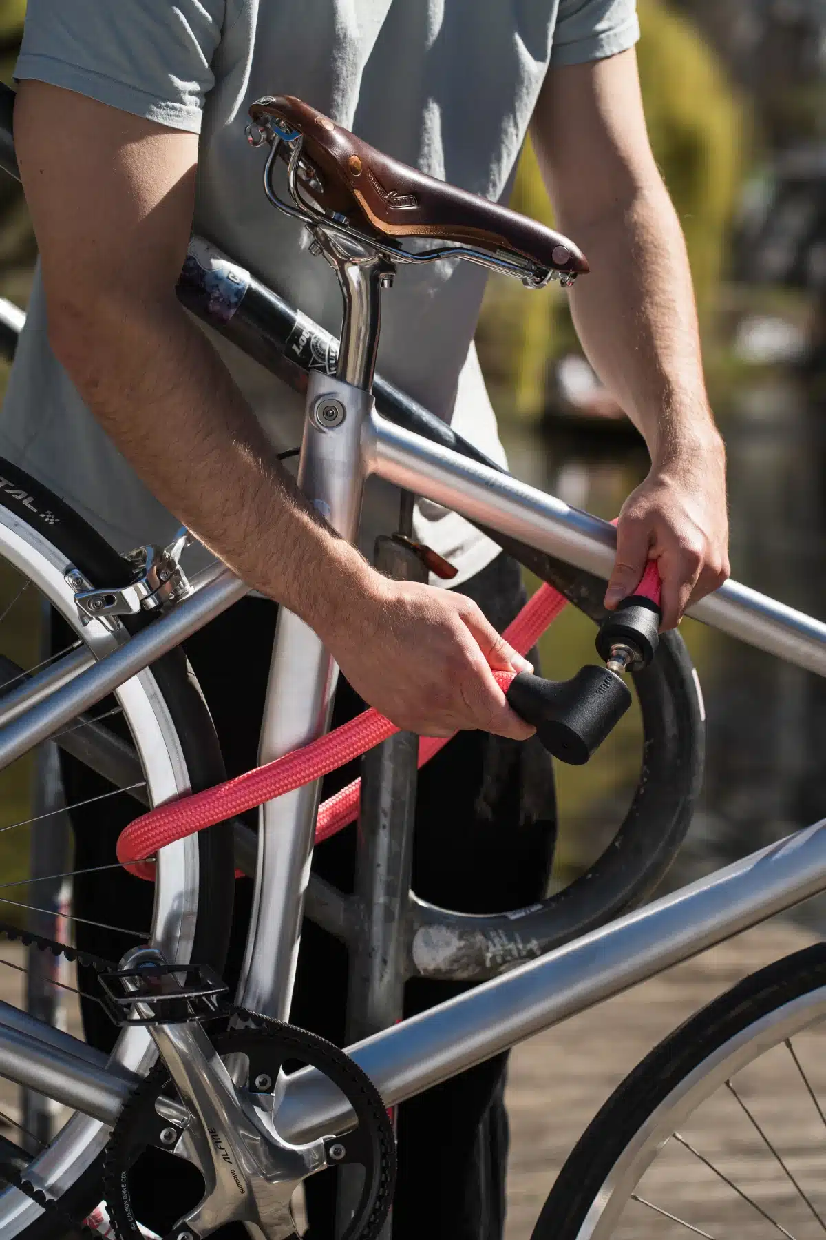 pinkes texlock orbit Textilschloss sichert mehrere Fahrradteile am Fahrradständer
