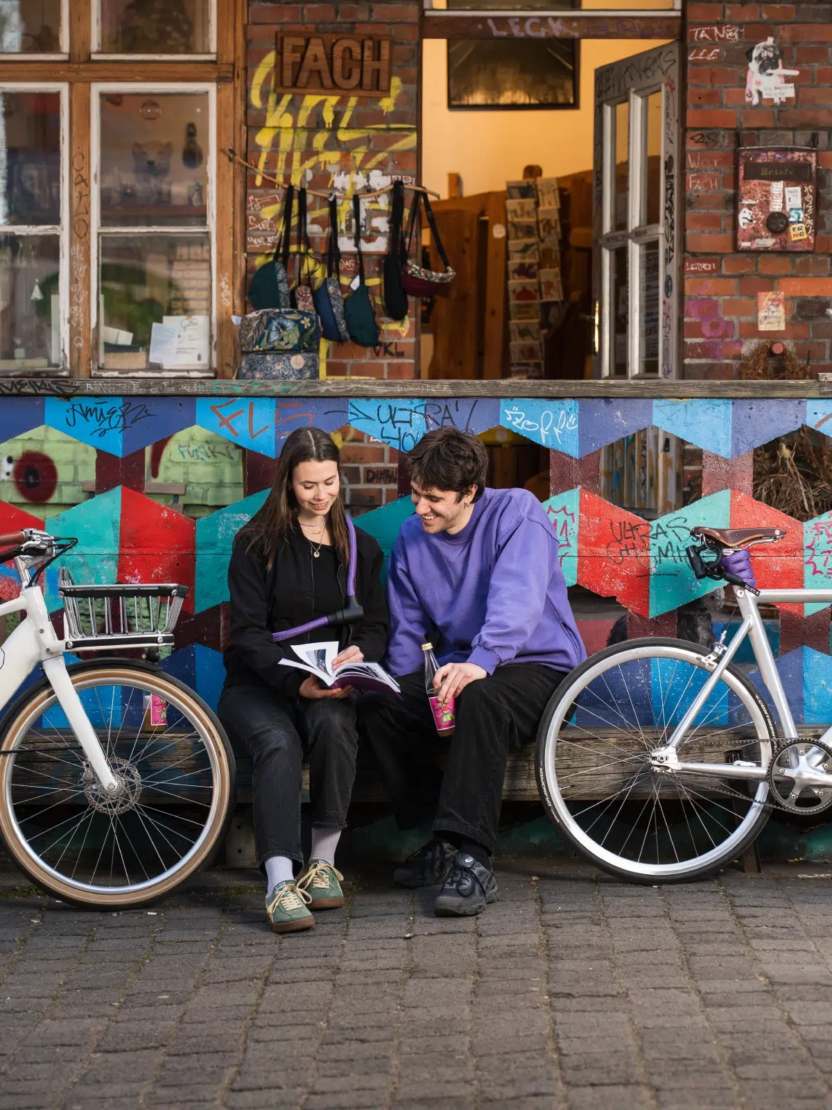 zwei Personen lesen mit limited colours lilanen Textilschlössern umgehängt und an Fahrrad befestigt